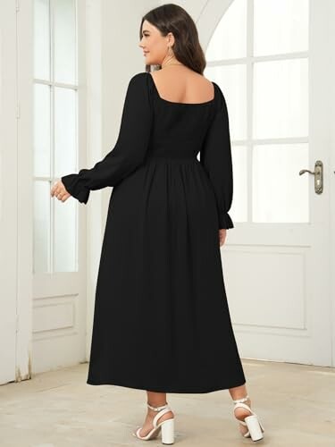 Woman wearing a black maxi dress standing in a room with white doors, showcasing the versatility of the dress.