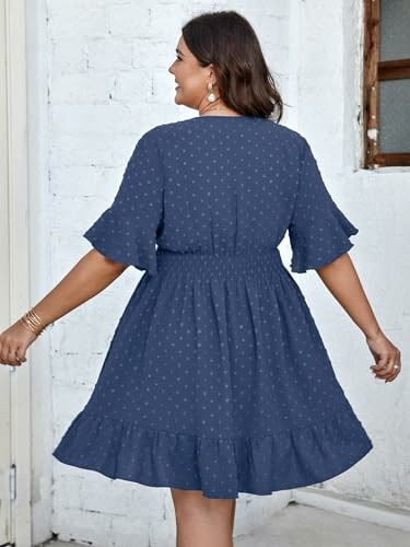 Woman wearing a blue ruffled dress with polka dots, viewed from the back.