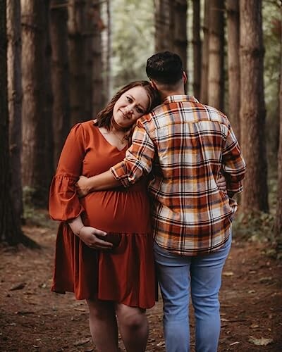 Pregnant woman and partner embracing in a forest.