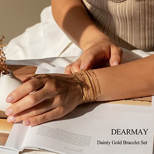 Person wearing dainty gold bracelet set