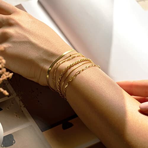 Arm adorned with multiple gold bracelets.