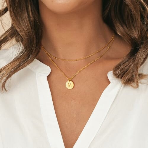 Woman wearing a gold necklace with an 'M' pendant