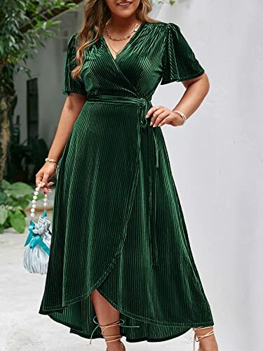 Woman wearing a green wrap dress standing against a white wall.