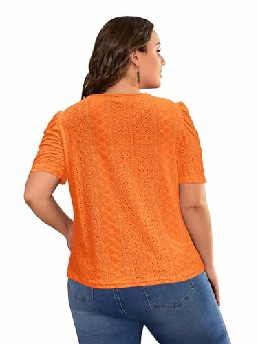 Back view of a woman wearing an orange lace top with short sleeves.