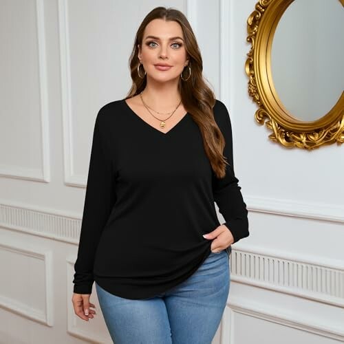 Woman in black top and jeans standing indoors