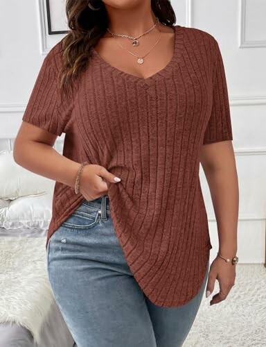 Woman wearing a brown knitted top and jeans.