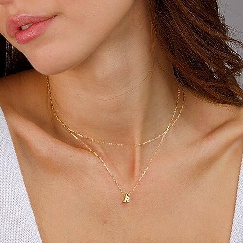 Woman wearing layered gold necklaces with a pendant