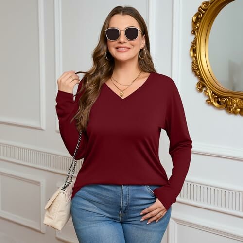 Woman wearing sunglasses and a burgundy top with a purse