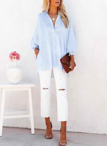 Woman wearing light blue shirt and white pants standing by a table with flowers.