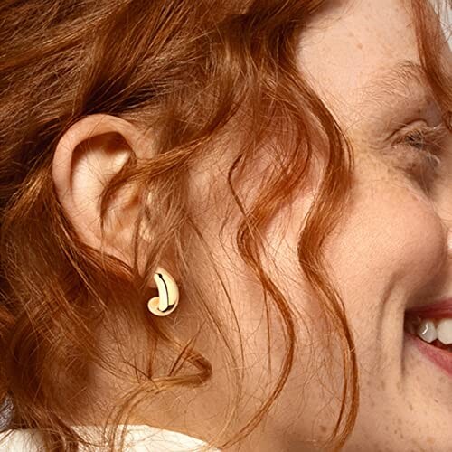 Woman with curly hair wearing banana-shaped earrings.