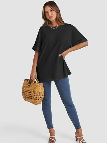 Woman in black top and jeans holding a woven bag