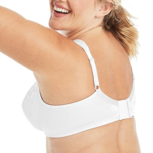 Woman smiling, wearing a white bra, viewed from the back.