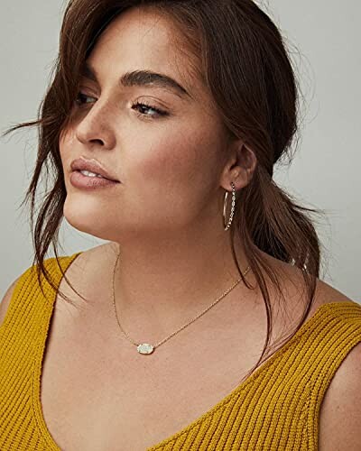 Woman in yellow top with necklace and necklace and hoop earrings